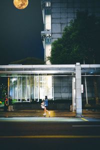 Man walking on road by building at night