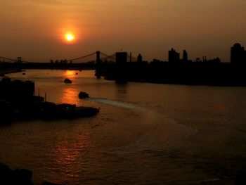 Silhouette bridge over sea against sky during sunset