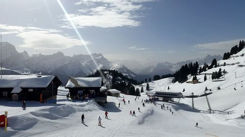 People skiing on snow at resort against sky