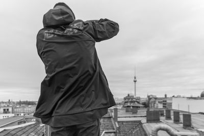 A man from behind on a roof in berlin. in the background the tv tower