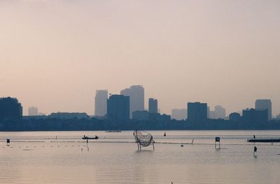 Sea by buildings against clear sky in city