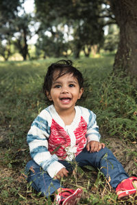 Cute baby boy 18-20 months sitting on grass, sensitivity to nature concept