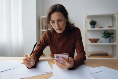 Young woman using mobile phone while sitting at home