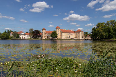 Scenic view of lake by buildings against sky
