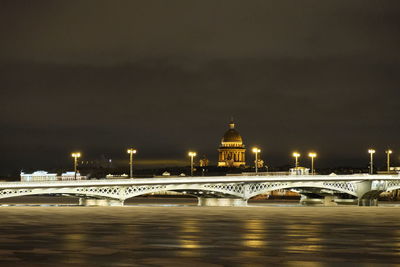 Illuminated bridge over river at night