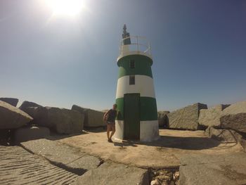 Full length of woman standing by lighthouse at alvor on sunny day