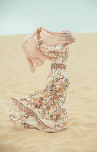 Woman in traditional clothing walking on sand at beach