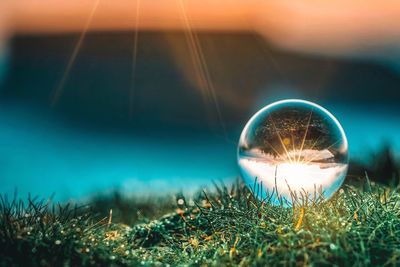 Close-up of crystal ball on field against bright sky