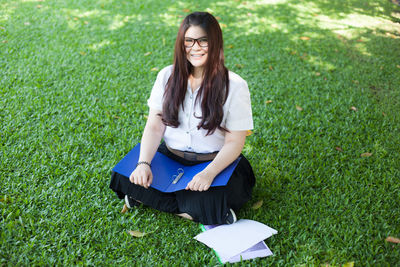 Young woman sitting file and book on grass