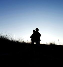 Silhouette people on field against clear sky