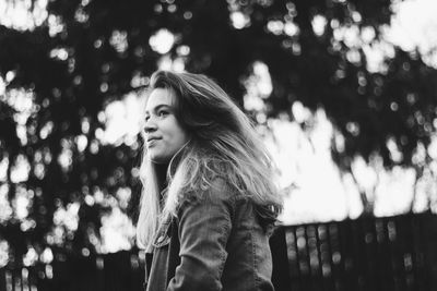 Woman looking away against trees