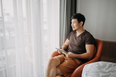 Young woman using mobile phone while sitting on sofa at home