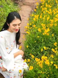 Girl crouching by yellow blooming flowers in park