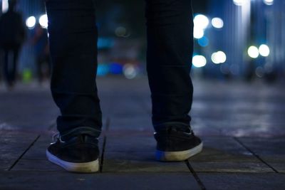 Low section of man standing on street at night