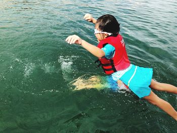 High angle view of girl wearing life jacket jumping in lake