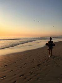 Full length of man walking on beach against clear sky