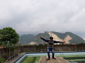 Rear view of man standing on mountain against sky