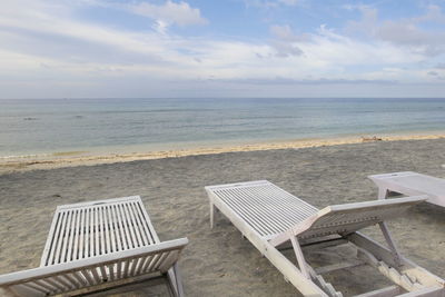 Chairs and table on beach against sky