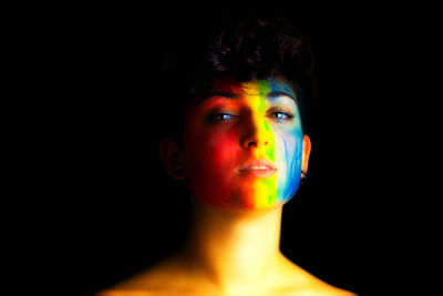 Young woman with multi colored hair against black background