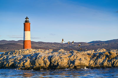 Lighthouse by sea against clear sky