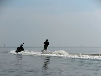 People wakeboarding in sea against sky