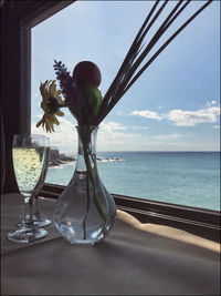 Flower vase on table by sea against sky