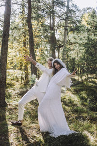 Cheerful newlywed bride and groom gesturing in forest