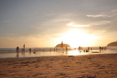 People on beach against sky during sunset
