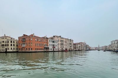 Buildings by river against sky