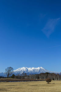 Scenic view of field and mountains against blue sky