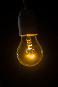 Low angle view of illuminated light bulb in darkroom