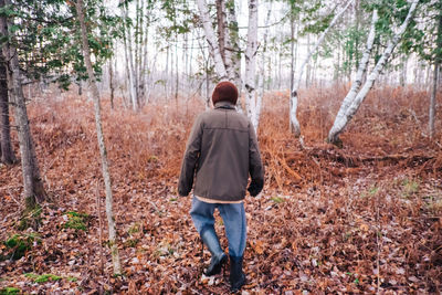 Rear view of man walking in forest during autumn