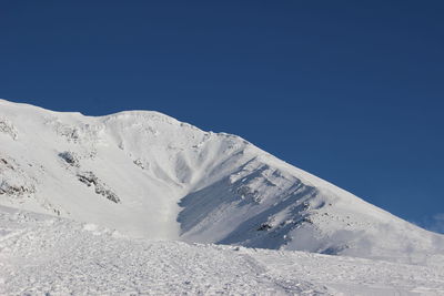 Scenic view of snowcapped mountains against clear blue sky