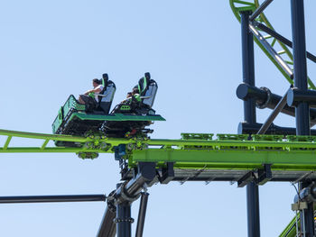 Low angle view of people working on bridge against clear sky