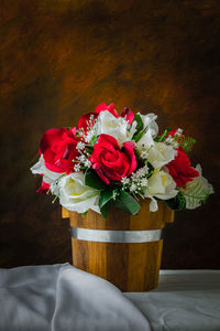 Red roses and white roses artificial on a brown background with space for text input.