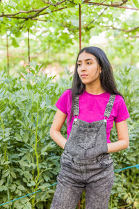 Young woman standing against plants