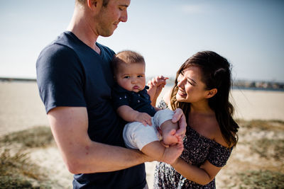 Father & mother looking at son while standing on beach