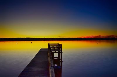 Pier on lake against sky during sunset