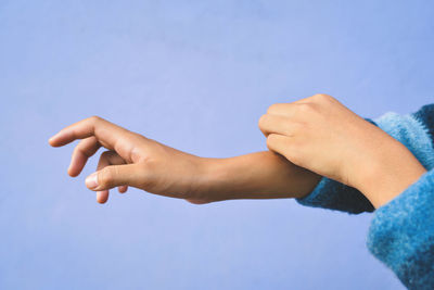 Cropped hands of woman against purple background