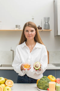 Portrait of smiling young woman sitting on table at home