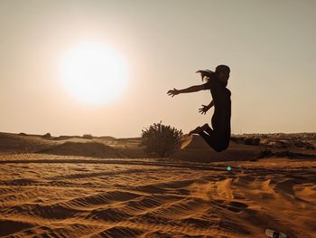 Side view of man jumping on sand