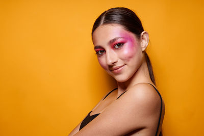 Close-up of young woman against yellow background