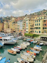 High angle view of boats moored at harbor against buildings in city