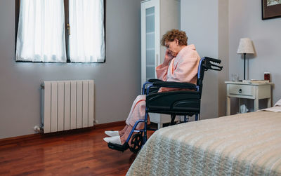 Side view of senior female patient sitting on wheelchair in hospital