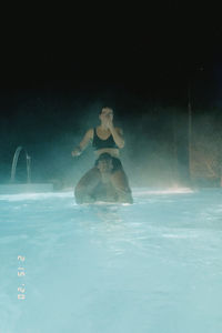 Young woman sitting in swimming pool during winter