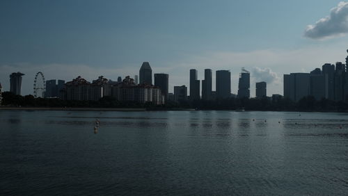 Sea by buildings against sky in city