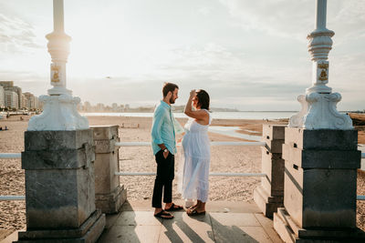 Couple standing by sea against sky