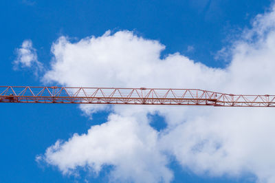 Low angle view of red crane against cloudy sky