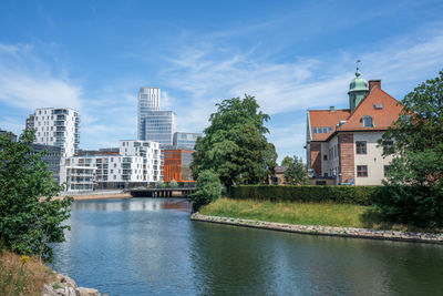 Buildings by river against sky