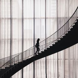 Silhouette woman walking on staircase in building
